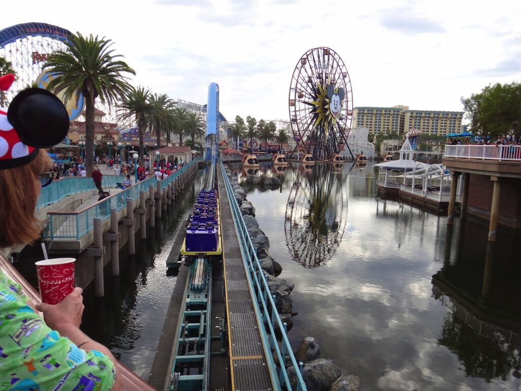 View of launch track of California Screamin' coaster at Disney's California Adventure, with Mickey's Fun Wheel in distance, seen over the shoulder of Kathryn Woodcock, only shoulder and part of head are visible, wearing aloha shirt and Minnie Mouse ear hat