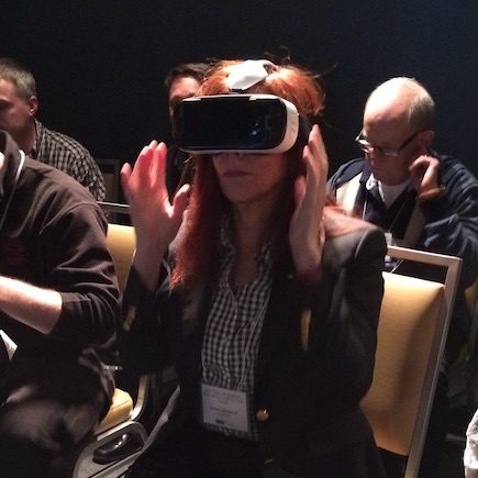 Kathryn Woodcock wears VR headset. Hands are in the air beside but not touching the headset.