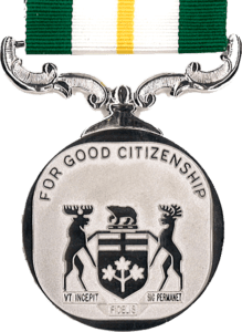 silver circular medal 36-mm diameter, Coat of Arms of the Province of Ontario fills the bottom 2/3rd of the disc with the words FOR GOOD CITIZENSHIP around the upper rim, suspended on scroll type mounting from a green ribbon 32-mm wide with central white stripe (15-mm) within which is centred a single gold stripe (3-mm)