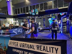 scene from the show floor with attendees experiencing VR hunting zombies or something