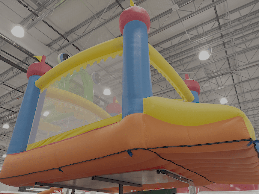 blue, yellow, and red inflatable bounce seen from below, with orange base, and small dark (blue) tabs around the edge