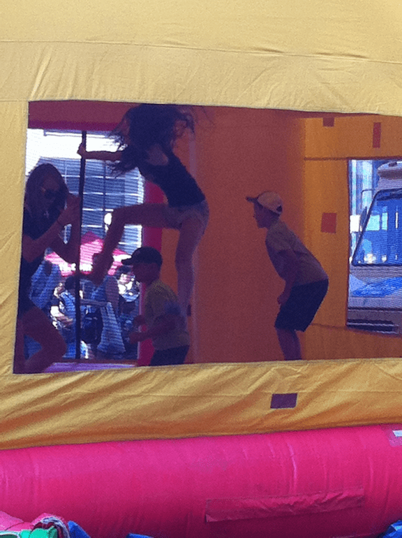 view into inflatable bounce, showing larger child jumping with wild abandon and a smaller child vulnerable to being knocked over or jumped on nearby